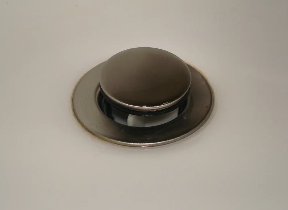 Close-up of a bathroom sink pop-up drain assembly and P-trap