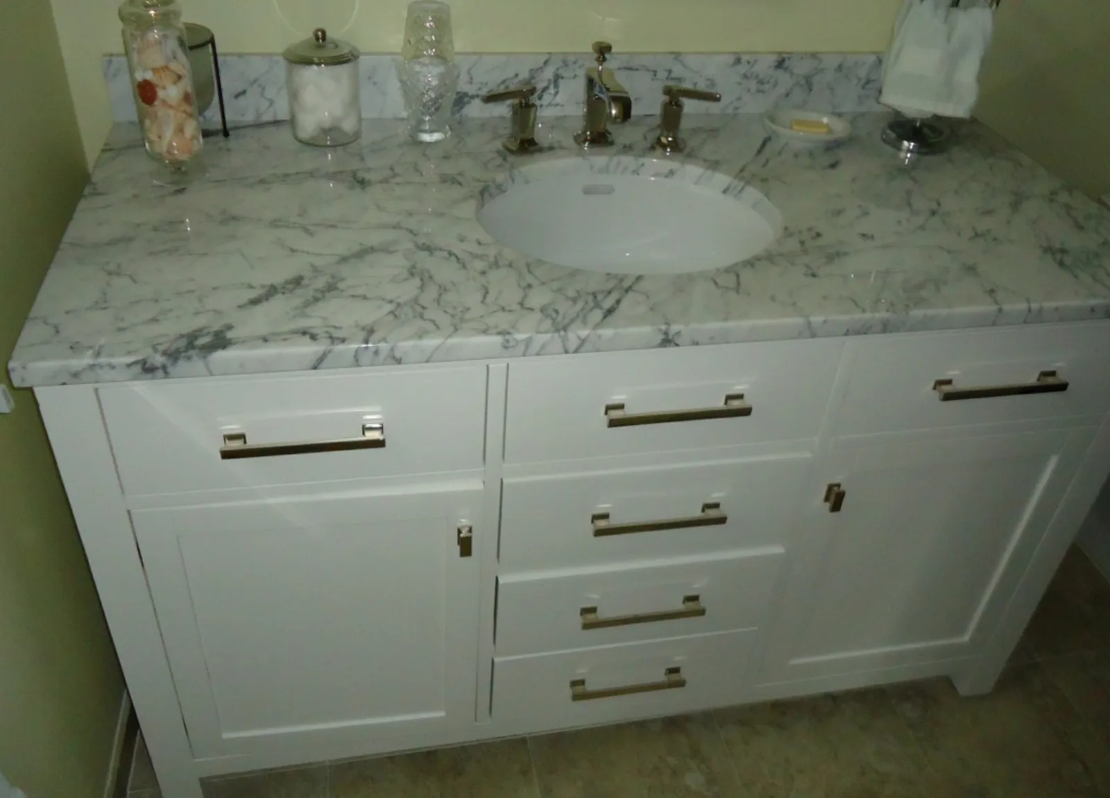 White bathroom vanity cabinet with marble-look top, undermount sink, and widespread faucet