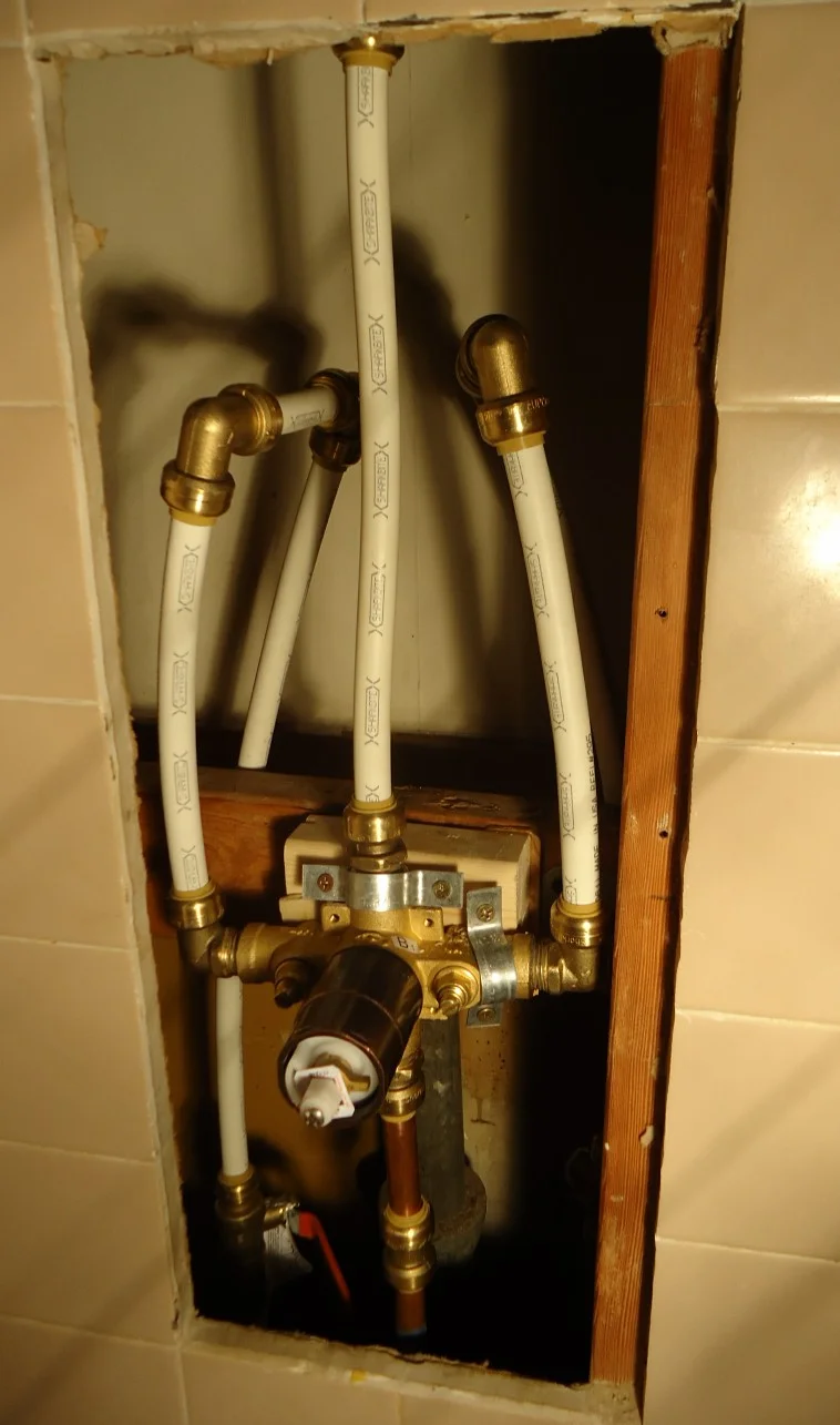 New shower diverter valve rough-in with PEX supply pipes attached, before wall finish