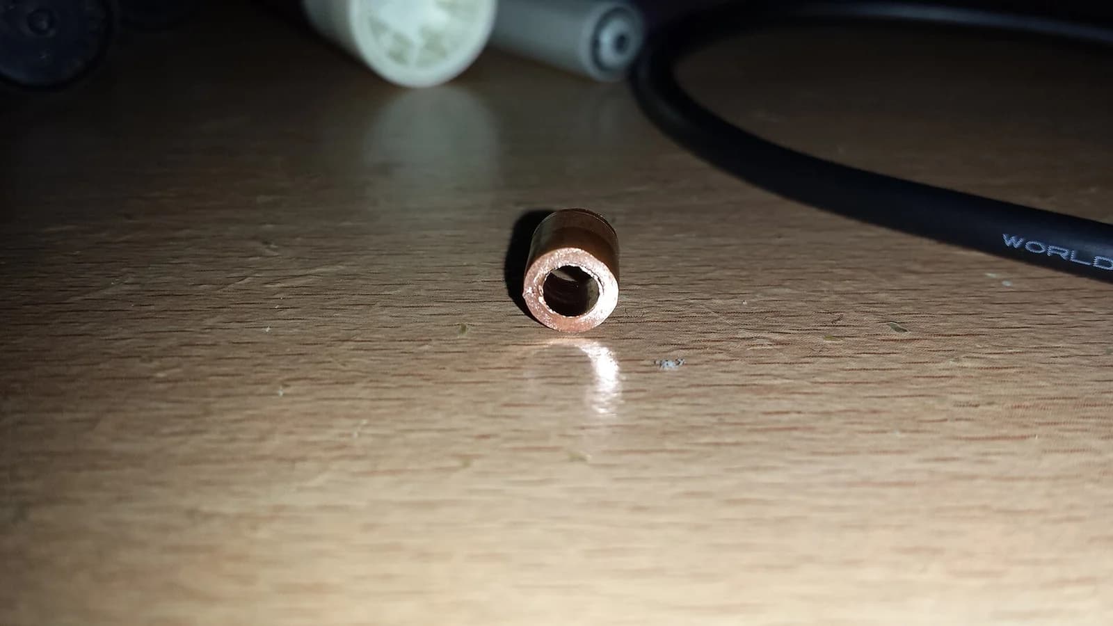 Cut piece of copper pipe with a coupling fitting on a wood table