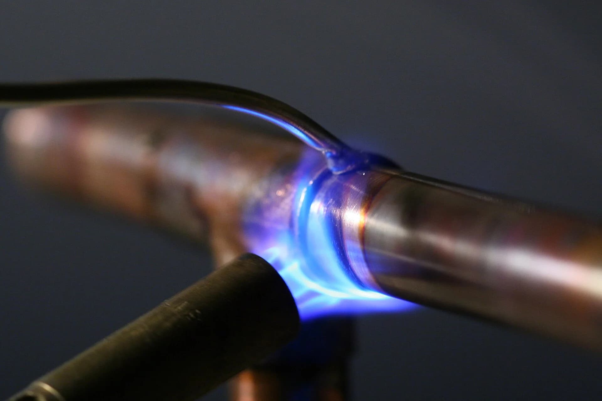 Propane torch flame heating a copper pipe joint as solder flows in