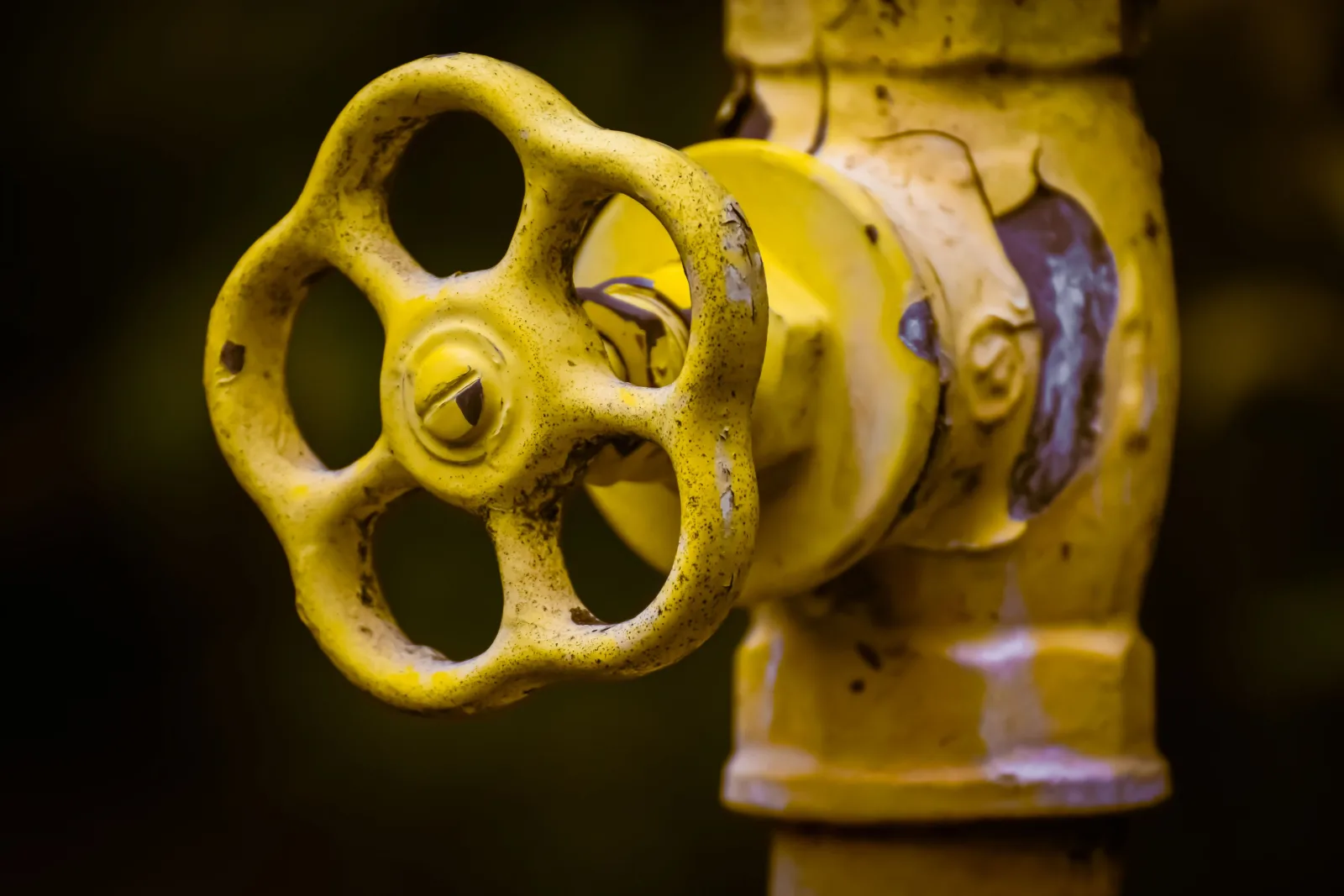 Close-up of a yellow-handled exterior shutoff valve on a water pipe