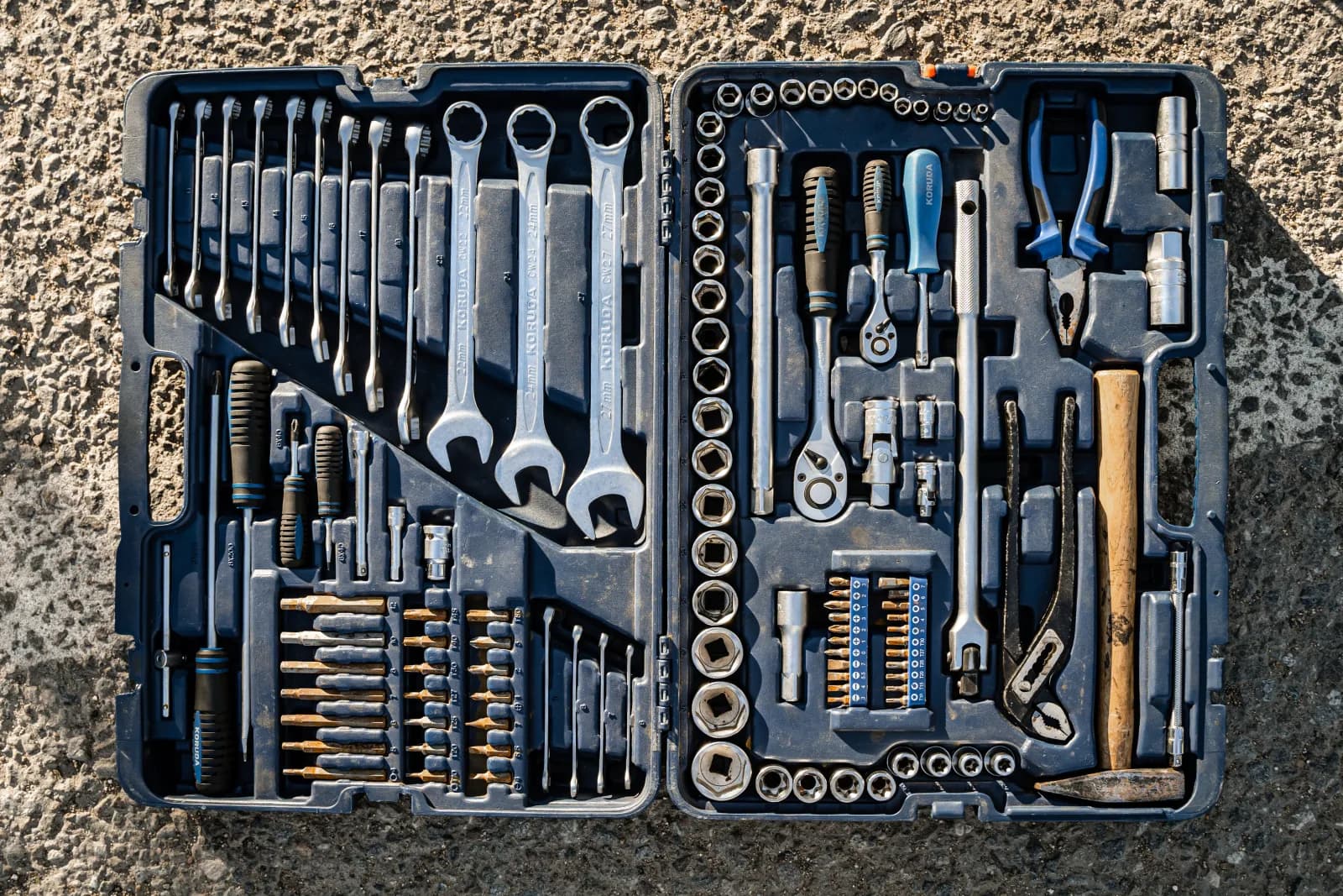 Open toolbox with combination wrenches, sockets, pliers, and screwdrivers used for plumbing service calls