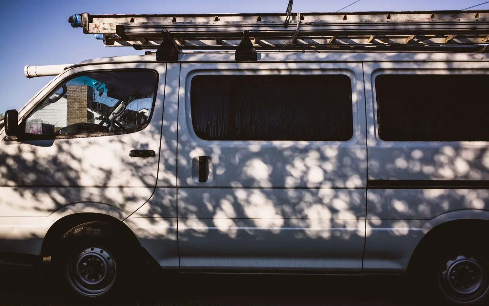 White plumbing service van with a ladder rack mounted on top