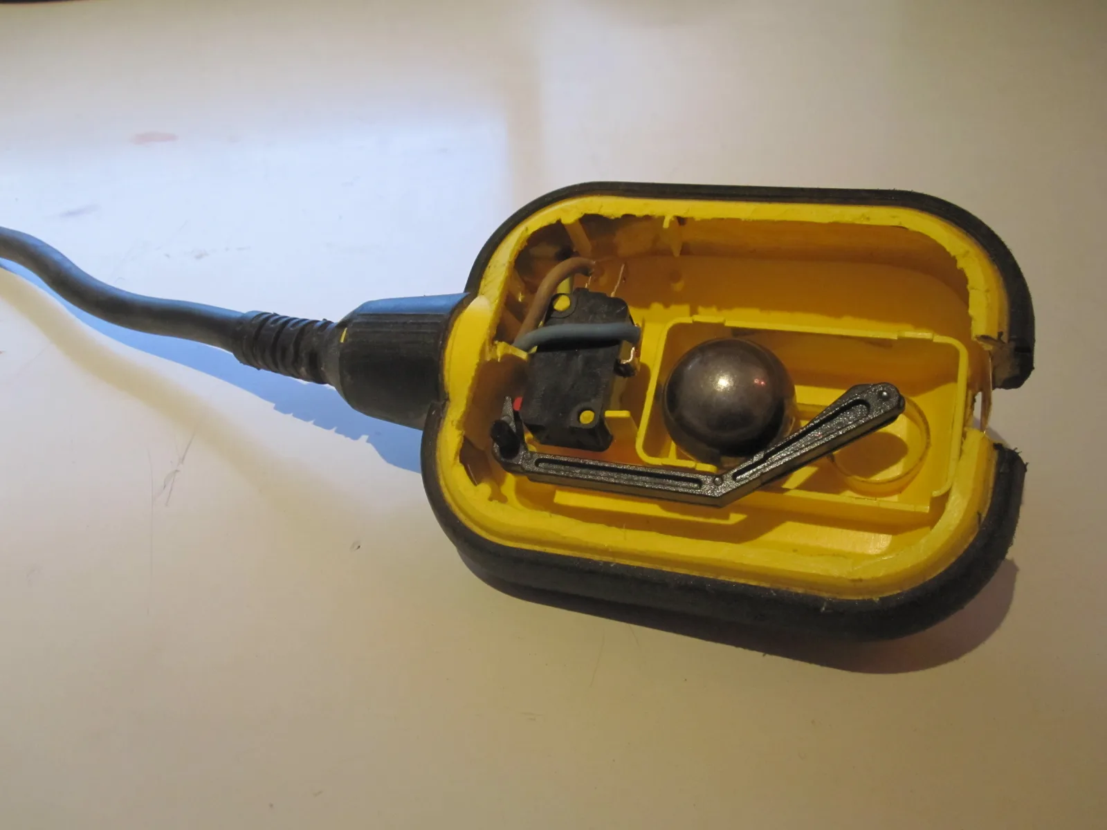 Opened sump pump float switch showing the internal tilt mechanism and microswitch