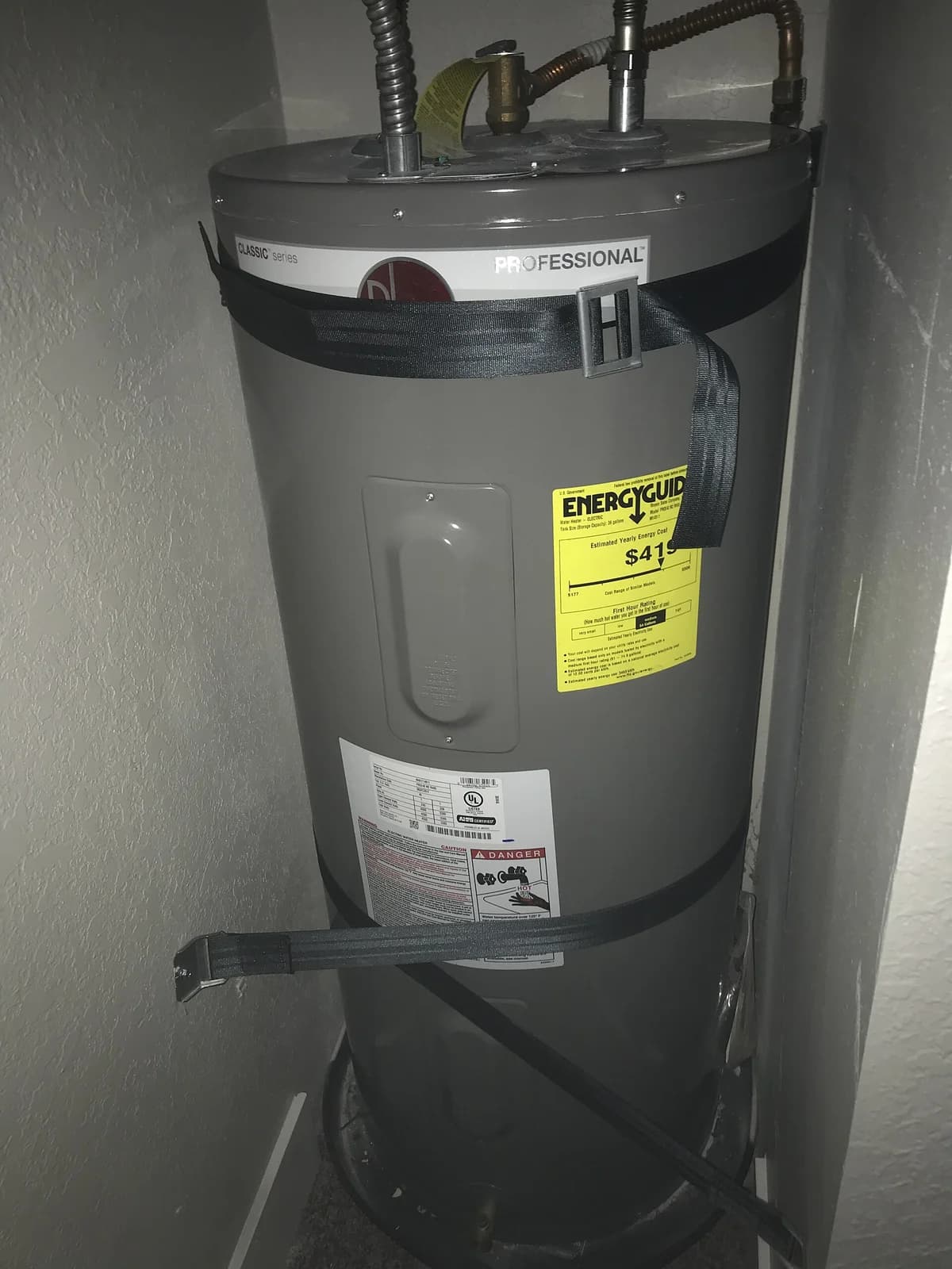 Electric tank water heater in a closet, secured with seismic restraint straps, EnergyGuide label visible