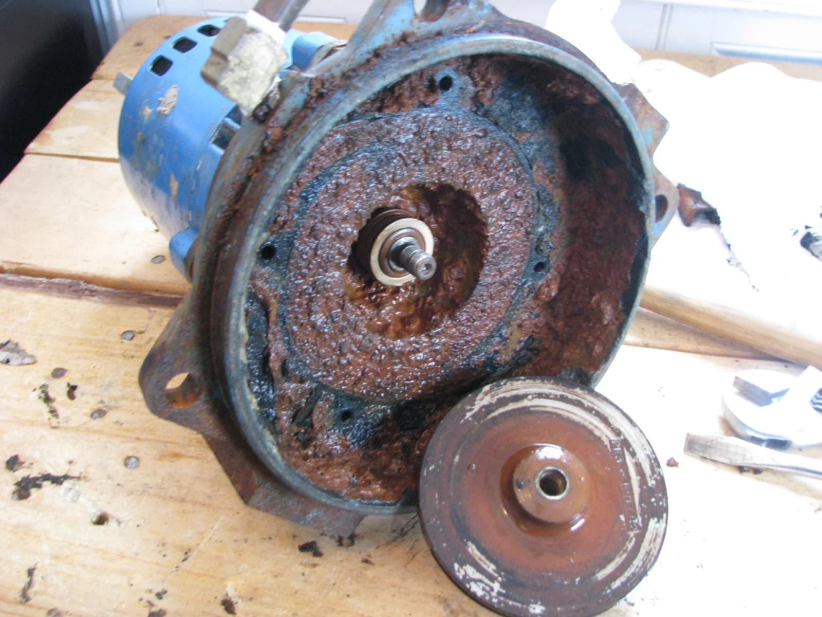 Disassembled well pump motor and impeller housing showing heavy mineral and rust buildup
